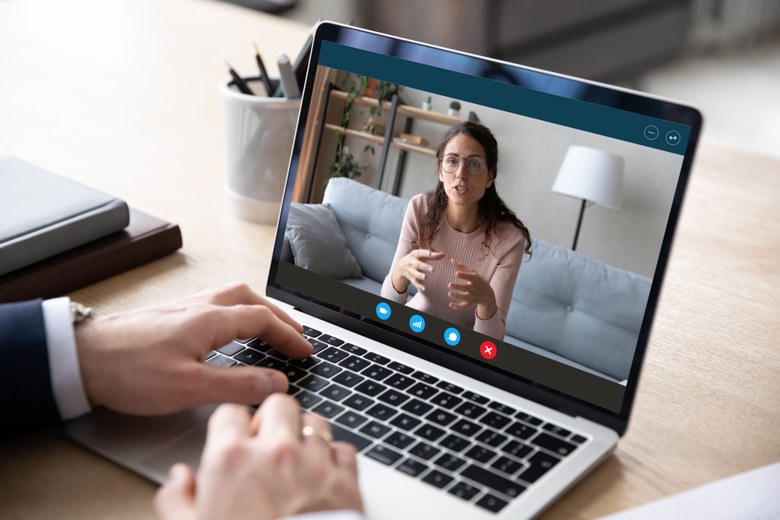 A person engages in a video call on a laptop, discussing intently while gesturing. A casual home setting is visible in the background.